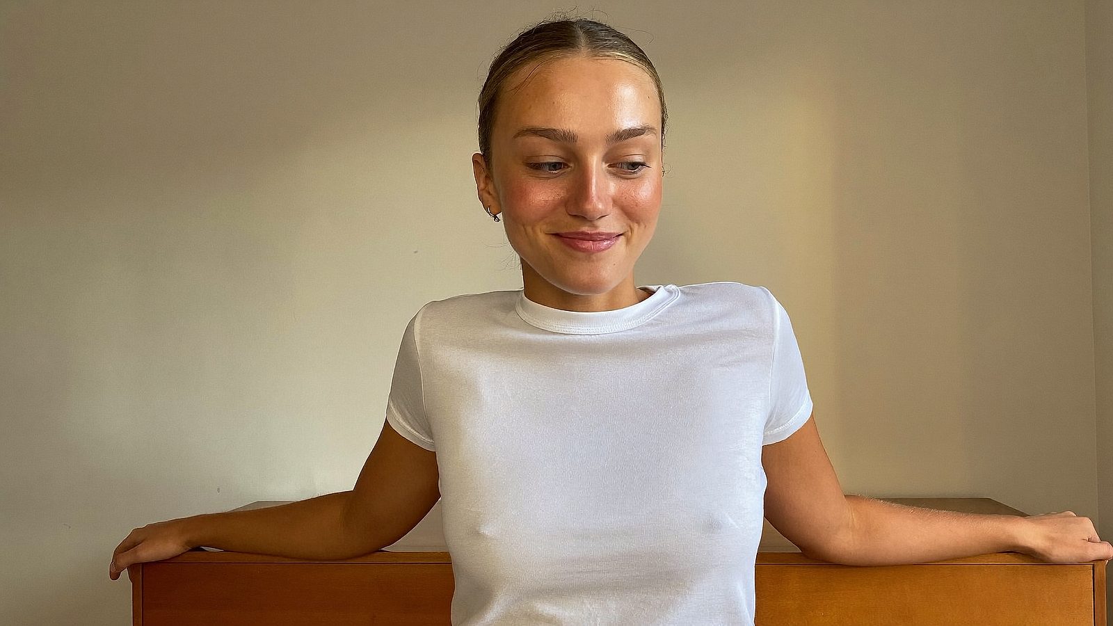 Bride-to-be with a natural golden tan standing in a bright bedroom