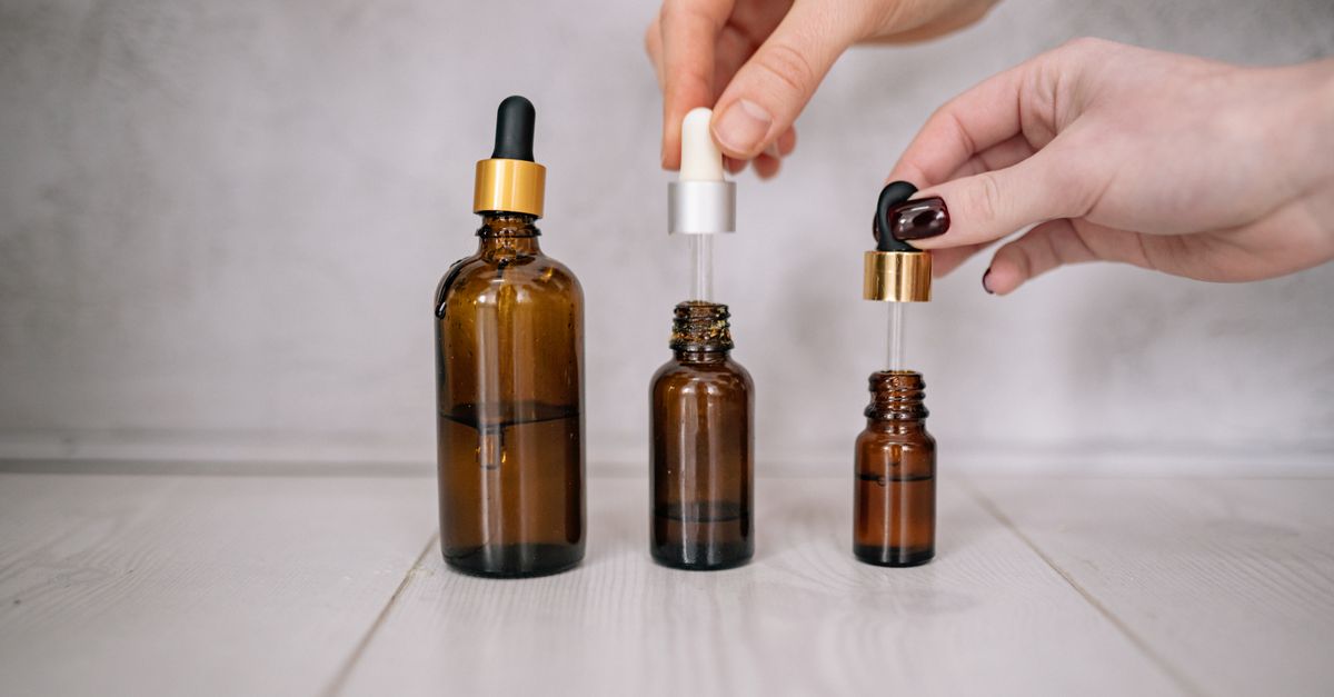 Hands holding three amber dropper bottles