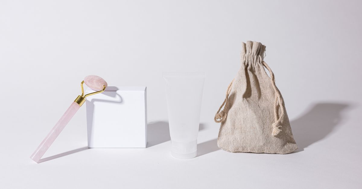 Blank cream tube with a rose quartz roller and linen pouch