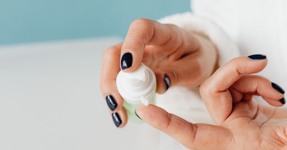 Hands pressing a pump of white lotion