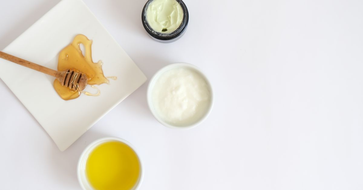 Honey, yogurt and oil beside a jar of natural cream