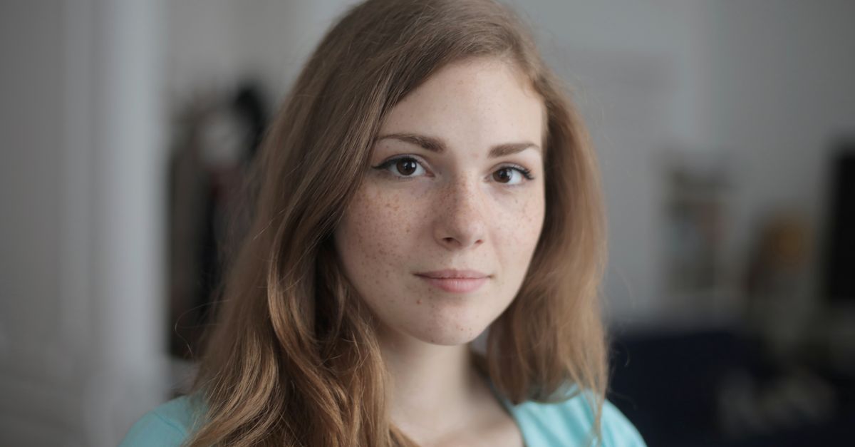 Young woman with fair freckled skin in soft indoor light