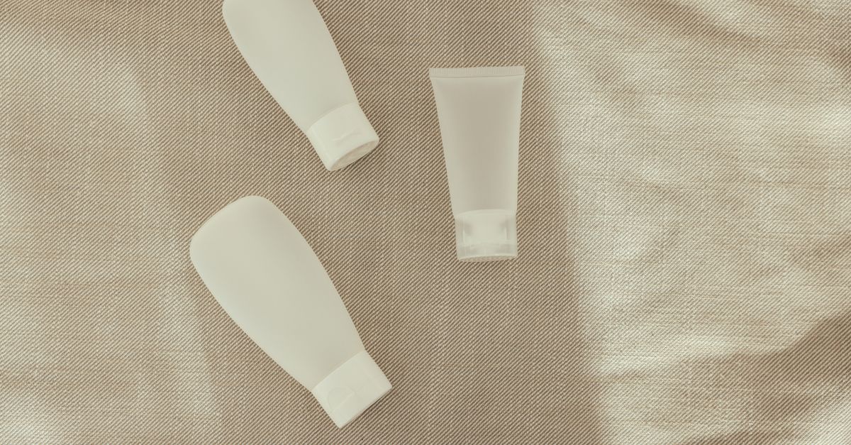 Plain cream tubes side by side on beige linen