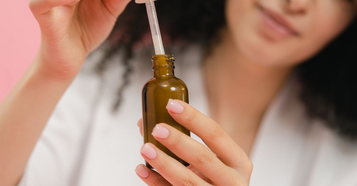 Woman holding an amber dropper bottle of face serum