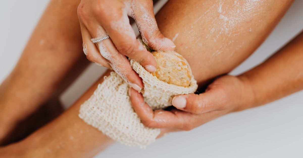 Woman exfoliating her leg with a natural sponge