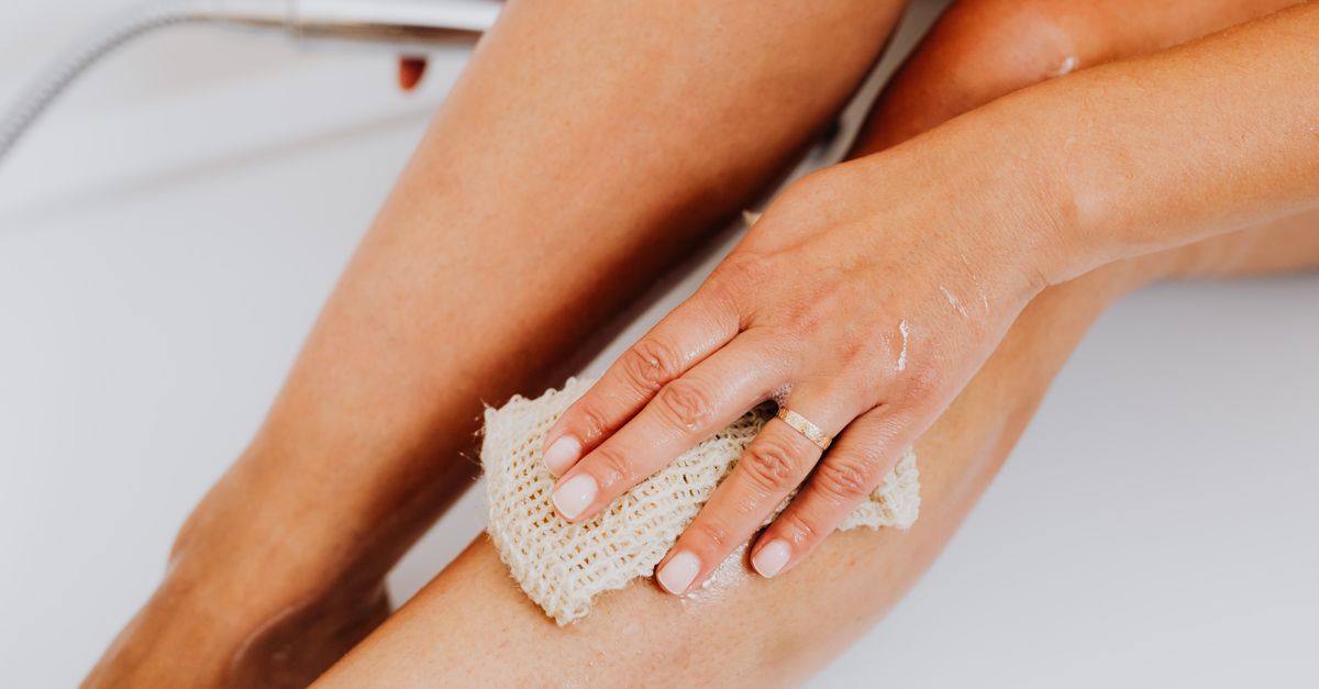 Woman scrubbing her leg with an exfoliating cloth in the bath