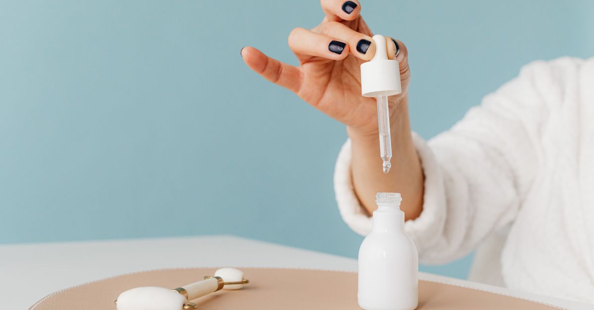 Hand lifting a pipette from a white serum bottle
