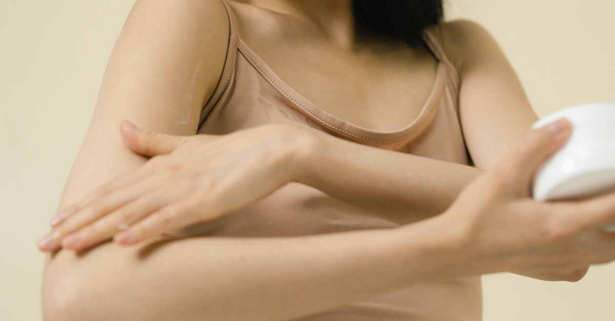 Woman applying cream to her upper arm